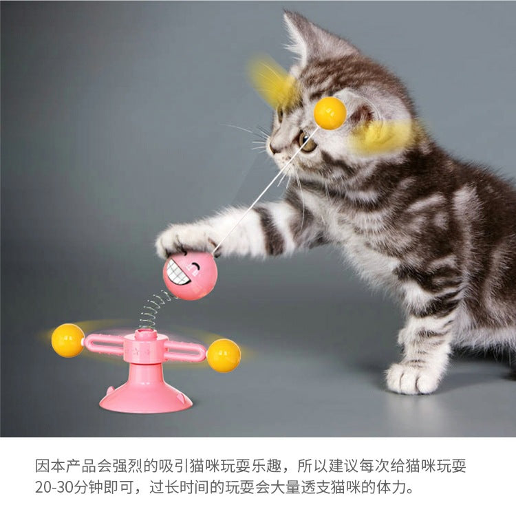 Cute tabby kitten playing with pink interactive cat toy featuring spinning balls and spring-loaded design.