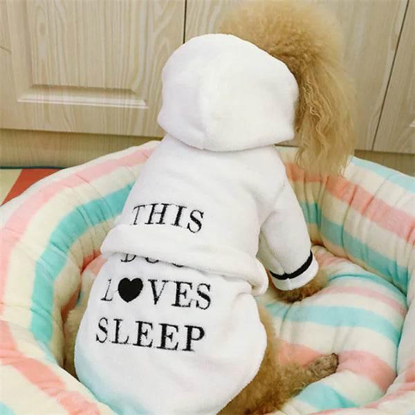 Dog in cozy white hoodie with 'This Dog Loves Sleep' text, nestled in pastel striped pet bed