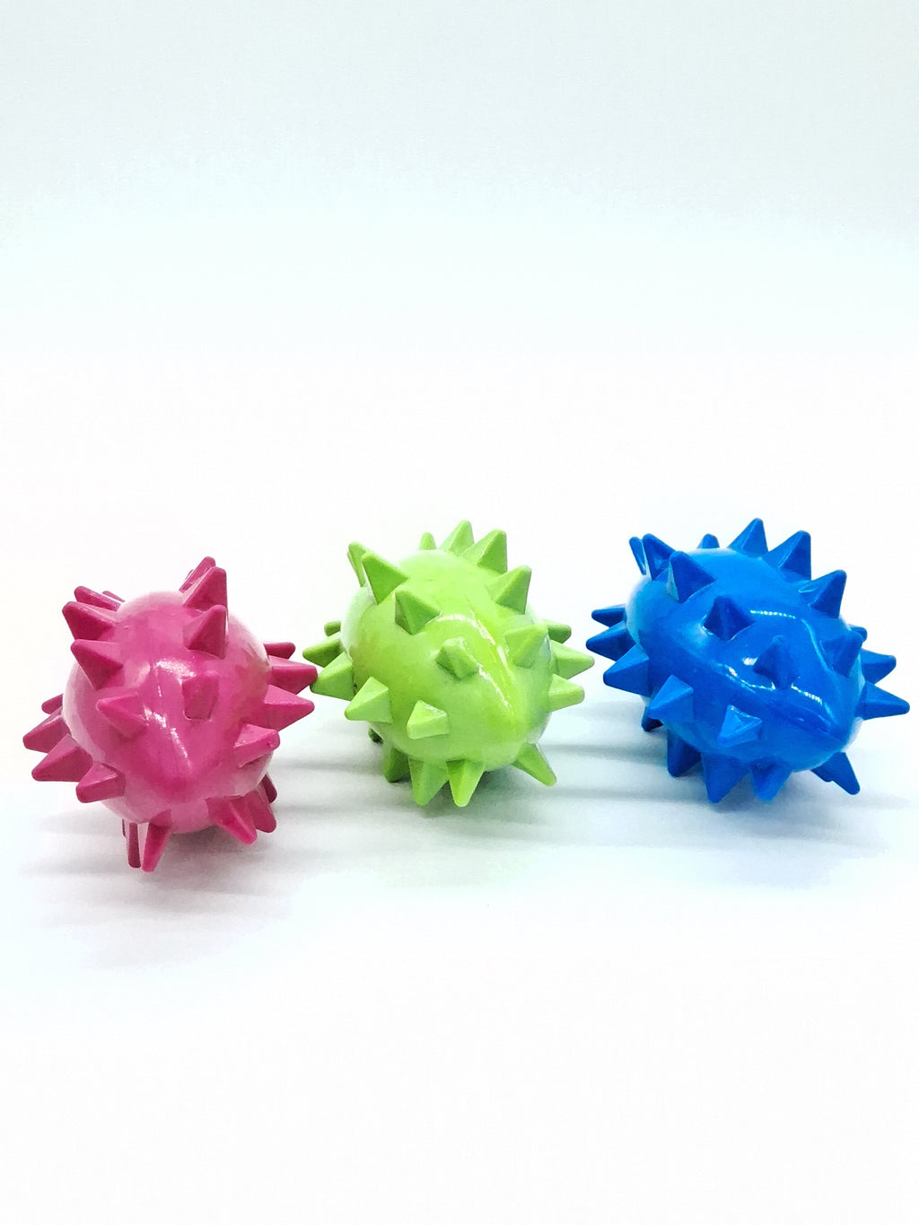Colorful spiky dog toys in pink, green, and blue for pet play and dental care