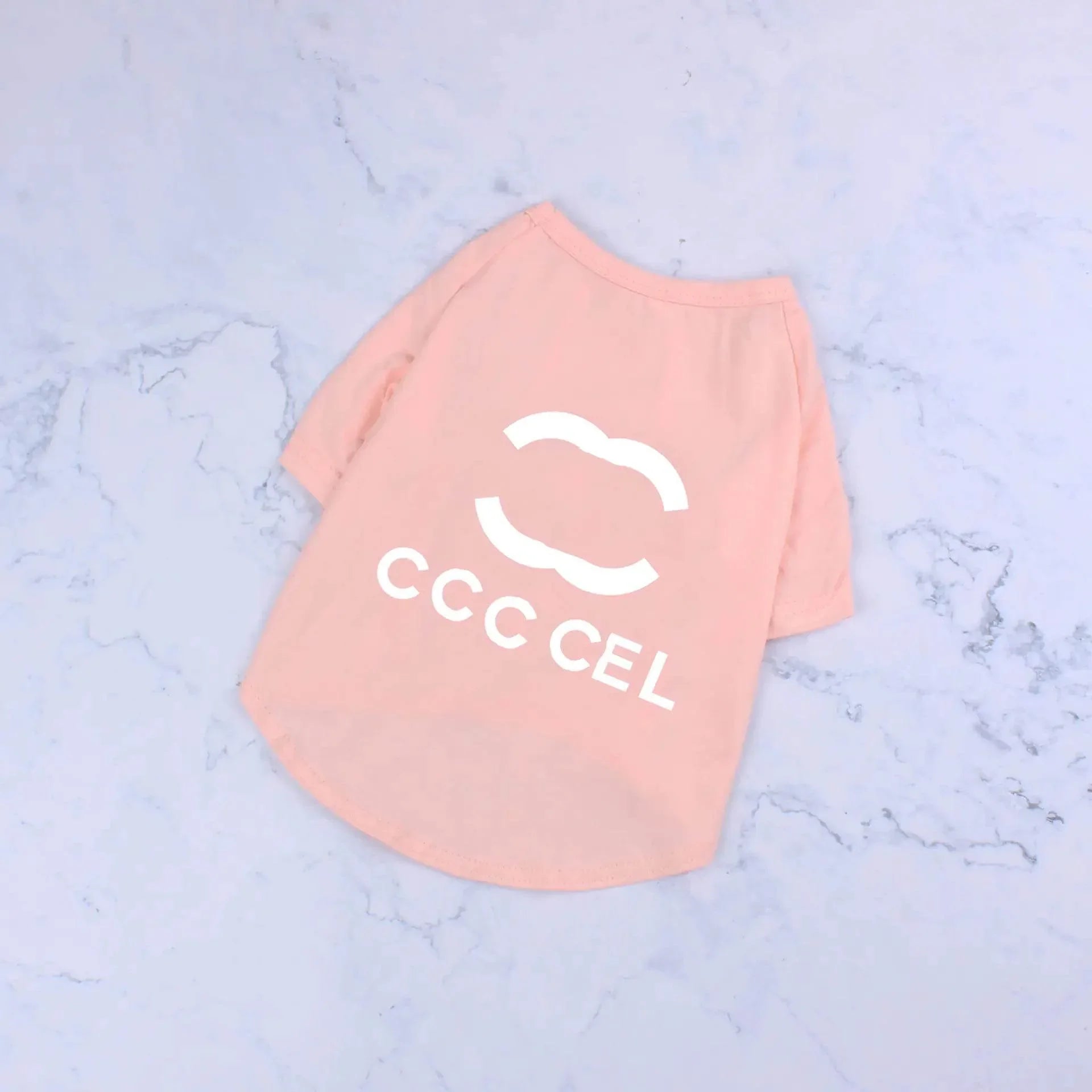 Pink pet T-shirt with CCC CEL logo on marble background, stylish dog or cat apparel