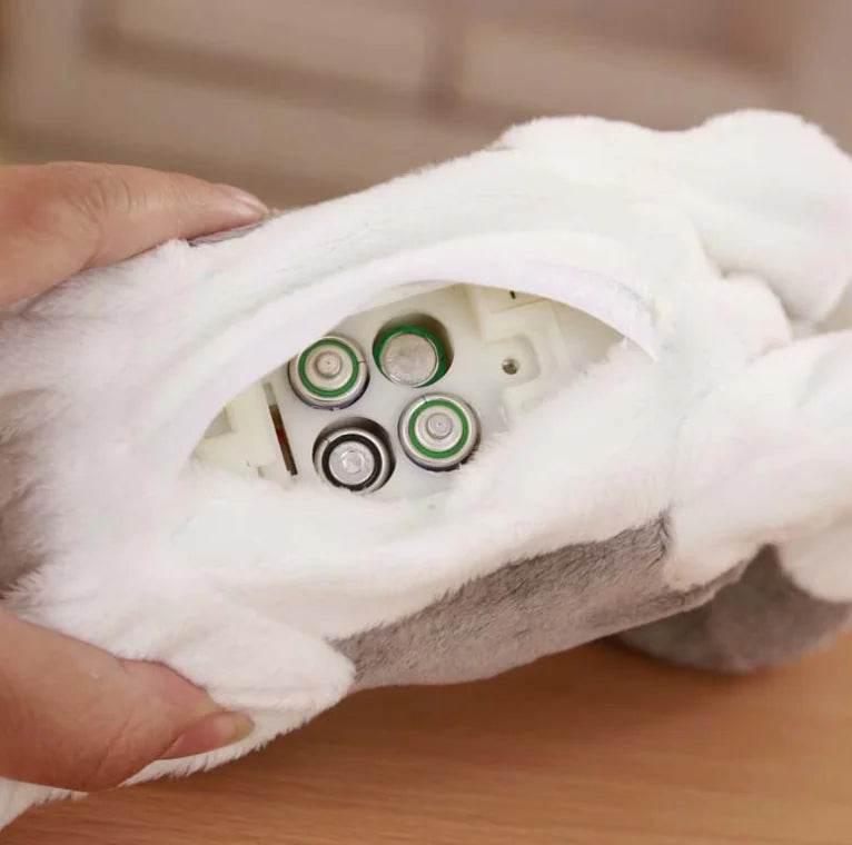 Fluffy white pet toy with battery compartment open, showing 4 AA batteries inside