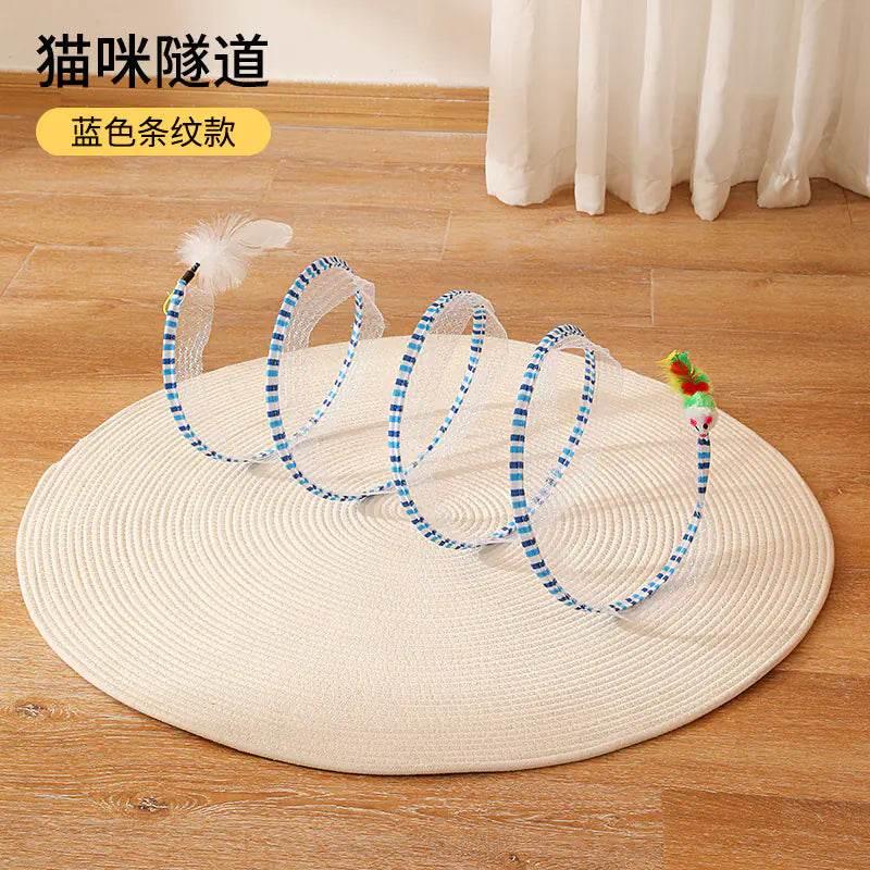 Blue striped cat tunnel toy with feather and pom-pom attachments on woven mat, ideal for indoor cat play and exercise.