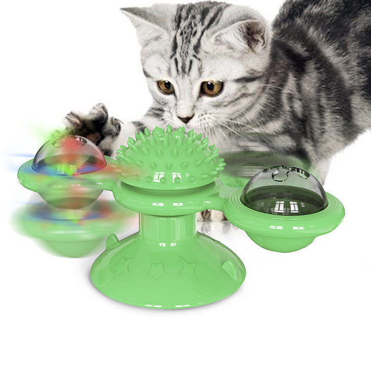 Gray tabby cat playing with green interactive cat toy featuring spinning balls and textured center for feline fun.